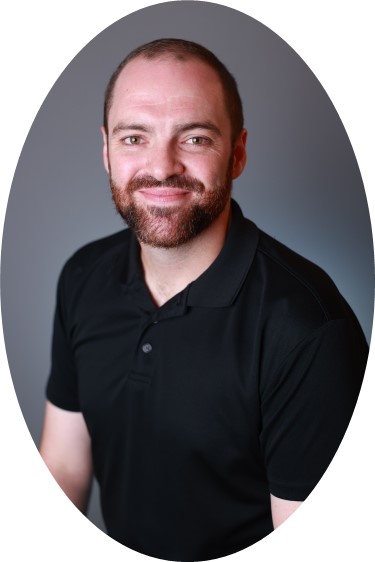 Middle aged white man with short hair, beard and black polo.