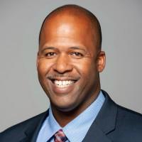 Bald black man smiling in a suit and tie